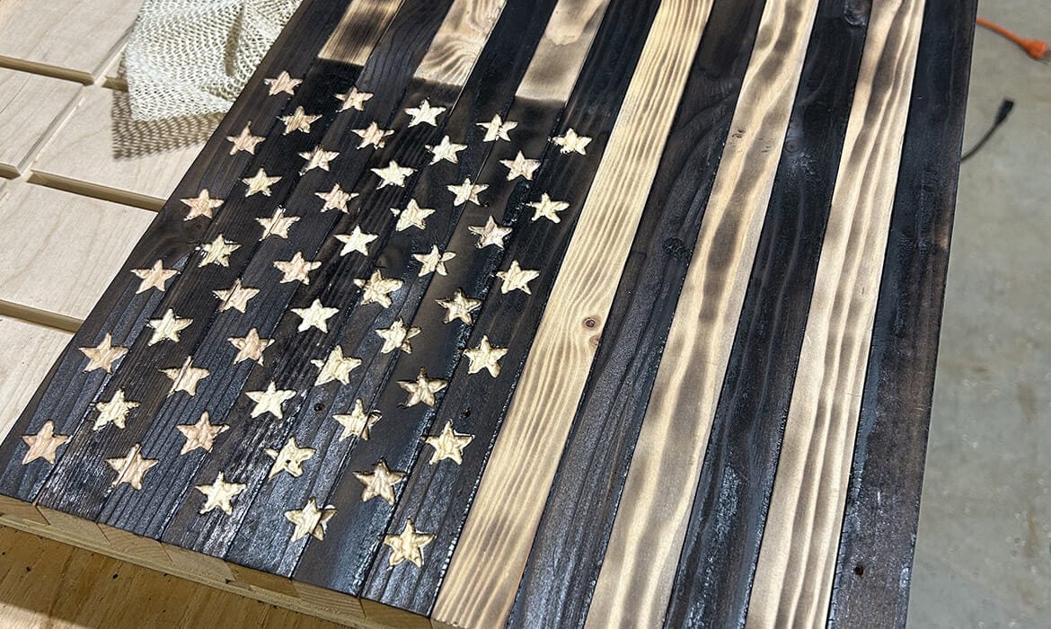 Rustic wooden American flag featuring carved stars and charred wood grain